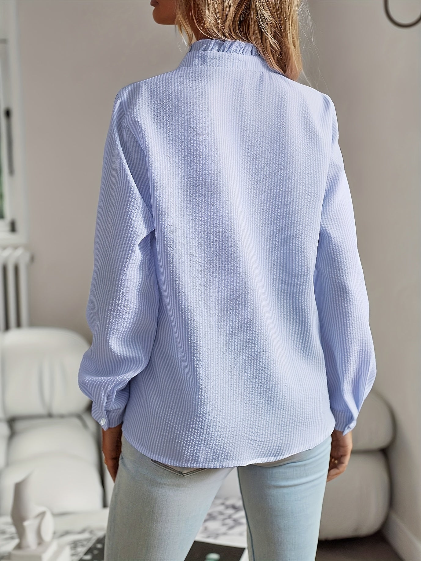 Camisa elegante de mulher às riscas com folhos, manga comprida, gola alta e detalhes de botões.