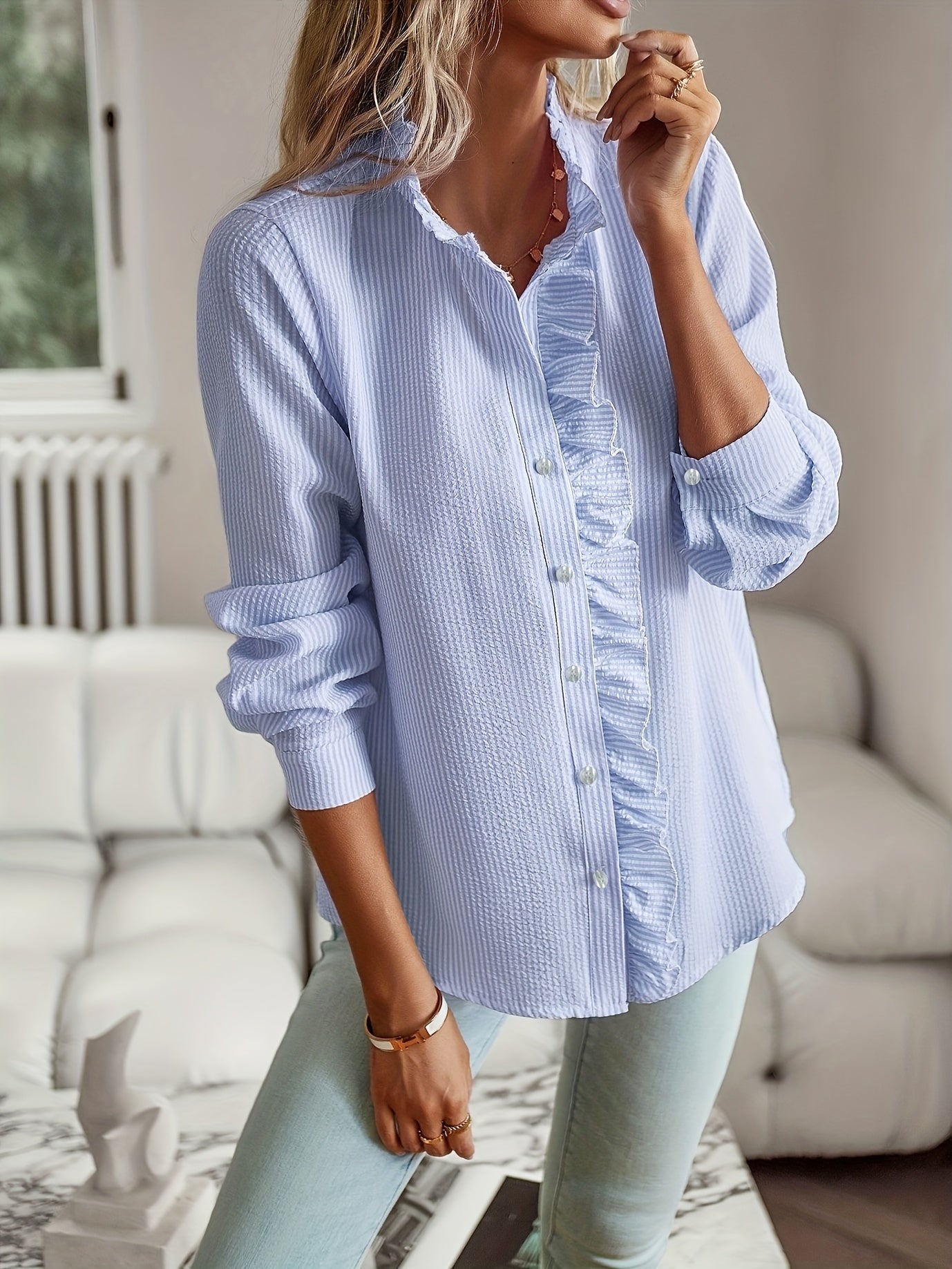 Camisa elegante de mulher às riscas com folhos, manga comprida, gola alta e detalhes de botões.